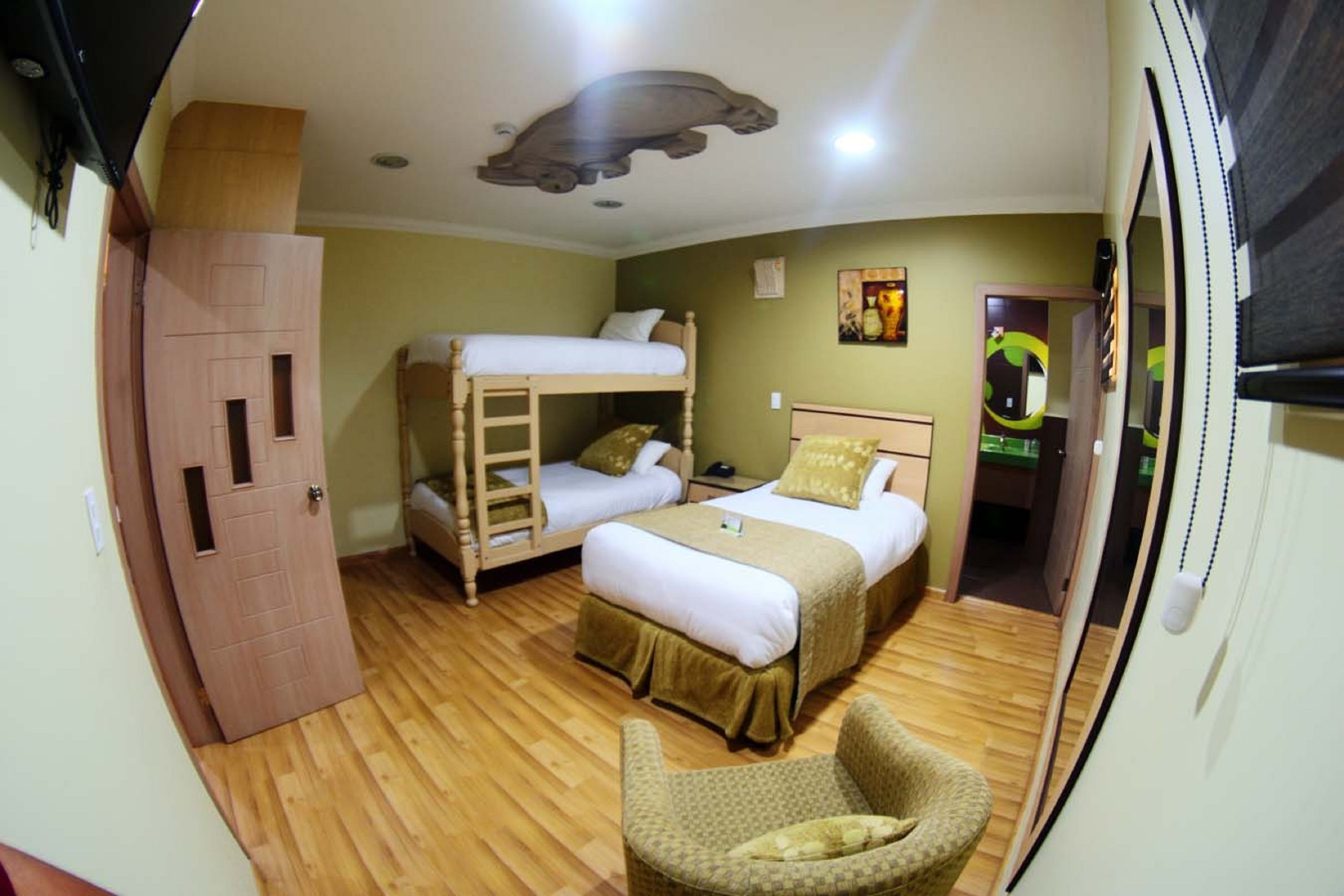 A room with two beds, a wooden wardrobe, a chair, and a ceiling light fixture.