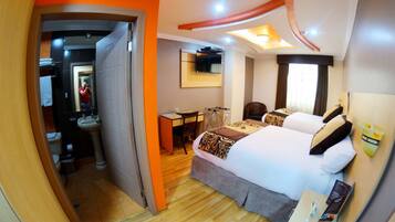 A hotel room with a bed, bedside table, and a mirror.