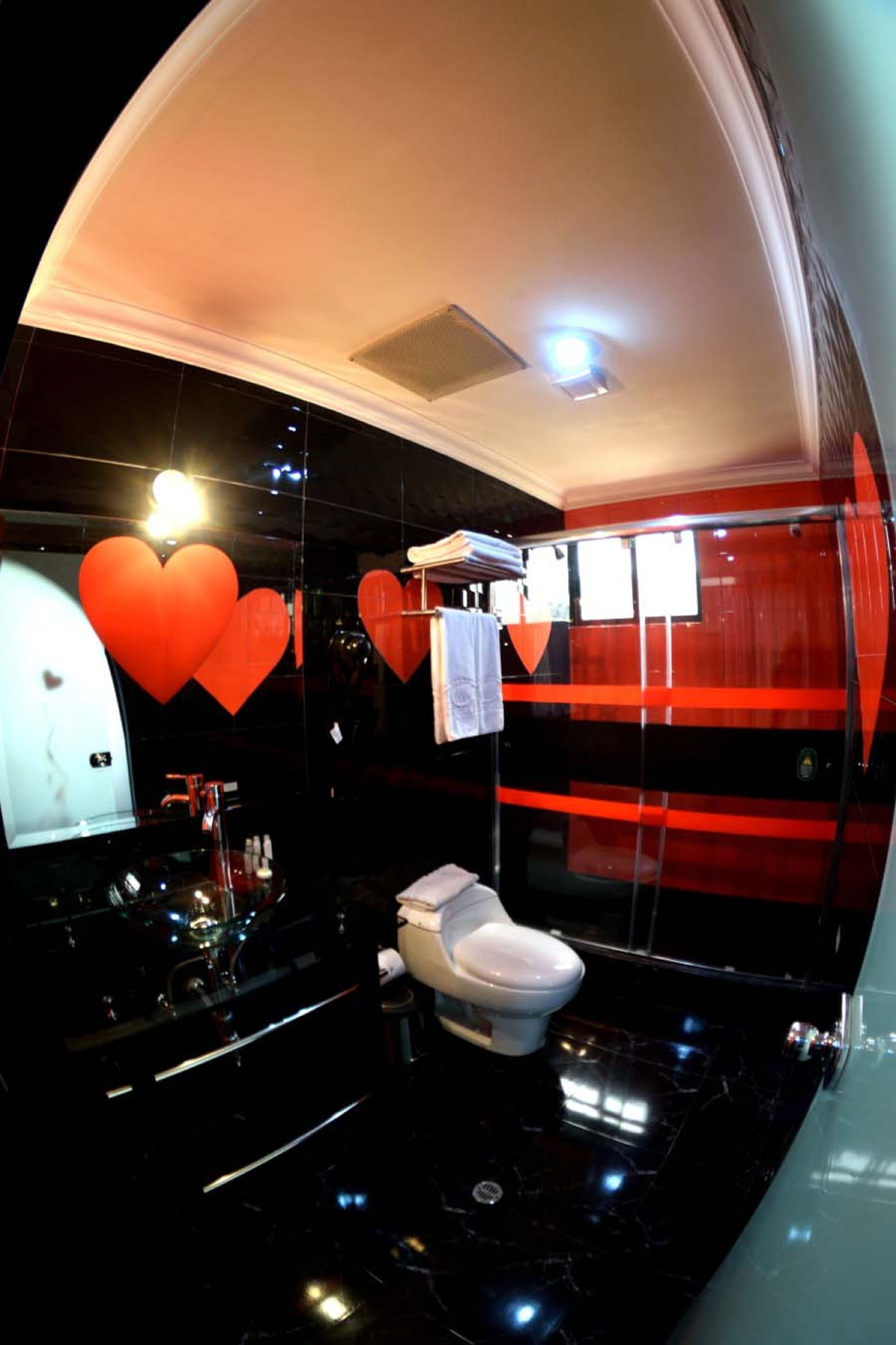 Un baño moderno con piso de mármol negro, inodoro blanco y cabina de ducha de vidrio.