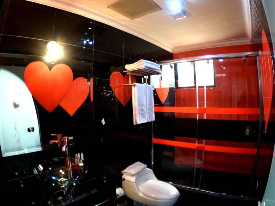 Un baño moderno con piso de mármol negro, inodoro blanco y cabina de ducha de vidrio.