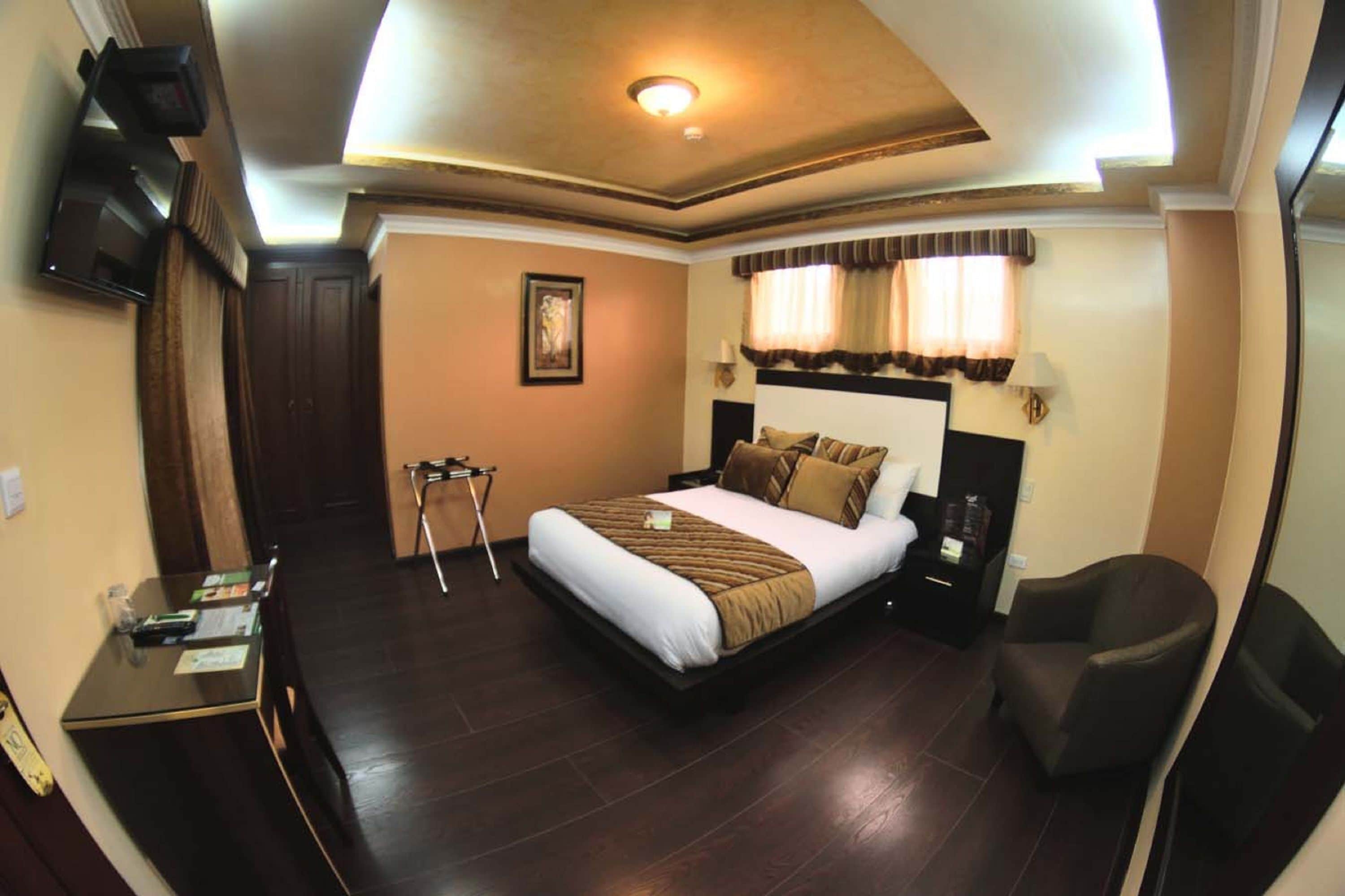 Una habitación de hotel con cama, sillón, escritorio y televisor.