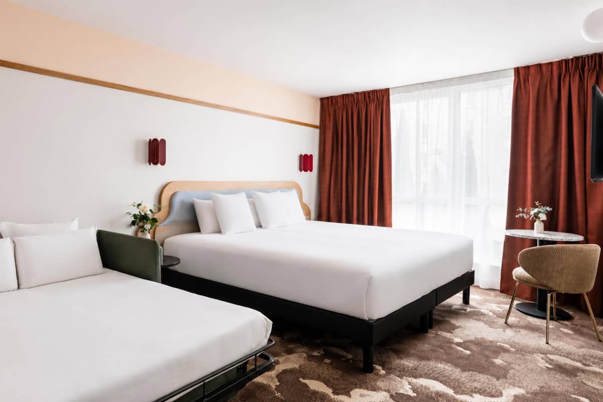 Une chambre d’hôtel avec deux lits, une petite table, une chaise et un téléviseur.