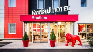 Un hotel llamado 'Kyrjad Hotel' con fachada roja y un cartel que indica 'Stadium'.