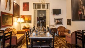 Ein Esszimmer mit einem langen Tisch, der für sechs Personen gedeckt ist, umgeben von Stühlen. Über dem Tisch hängt eine Chandelier, und an der Wand ist ein Fernseher angebracht.