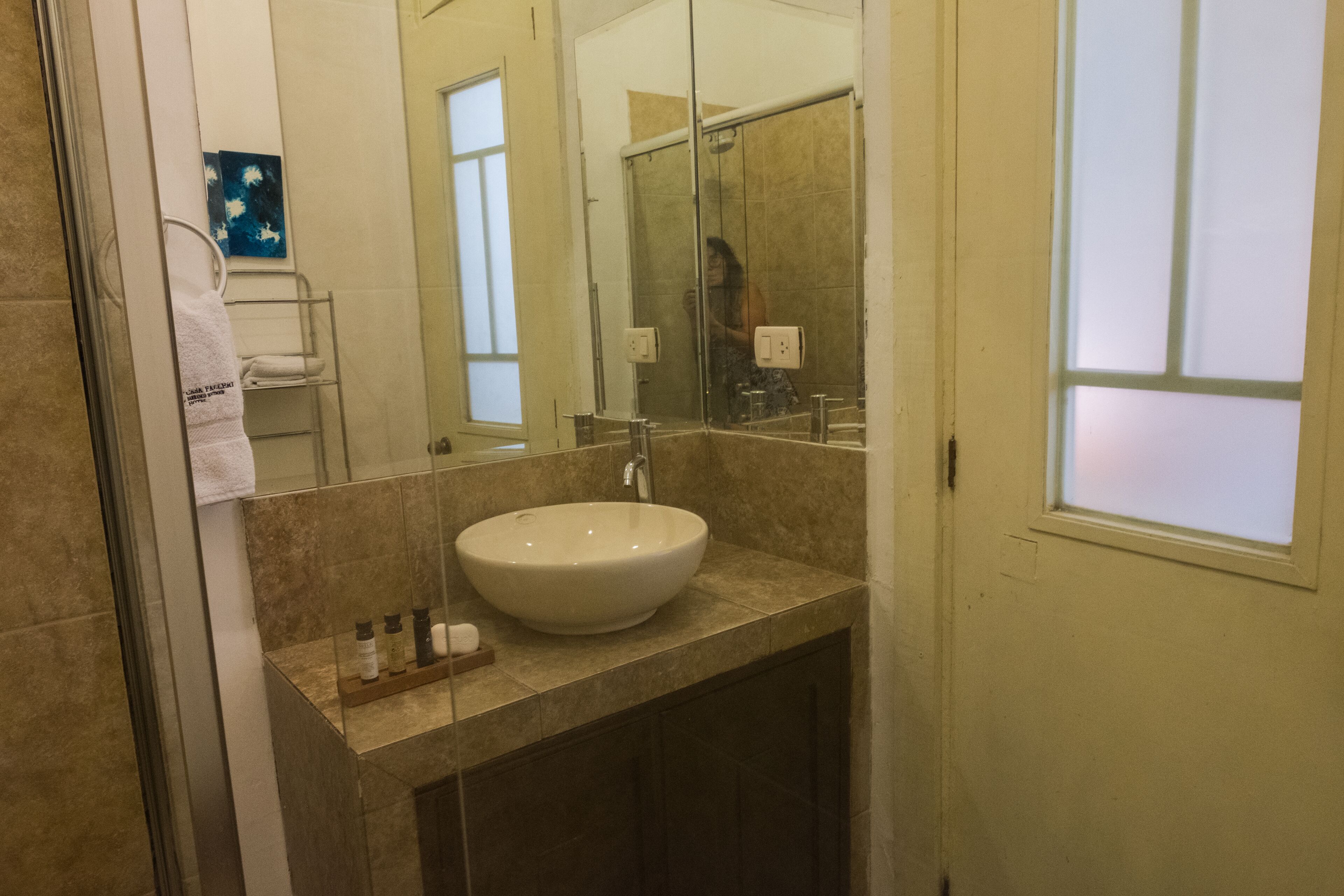 A bathroom with a large mirror, a sink, and a towel rack.
