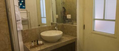 A bathroom with a large mirror, a sink, and a towel rack.