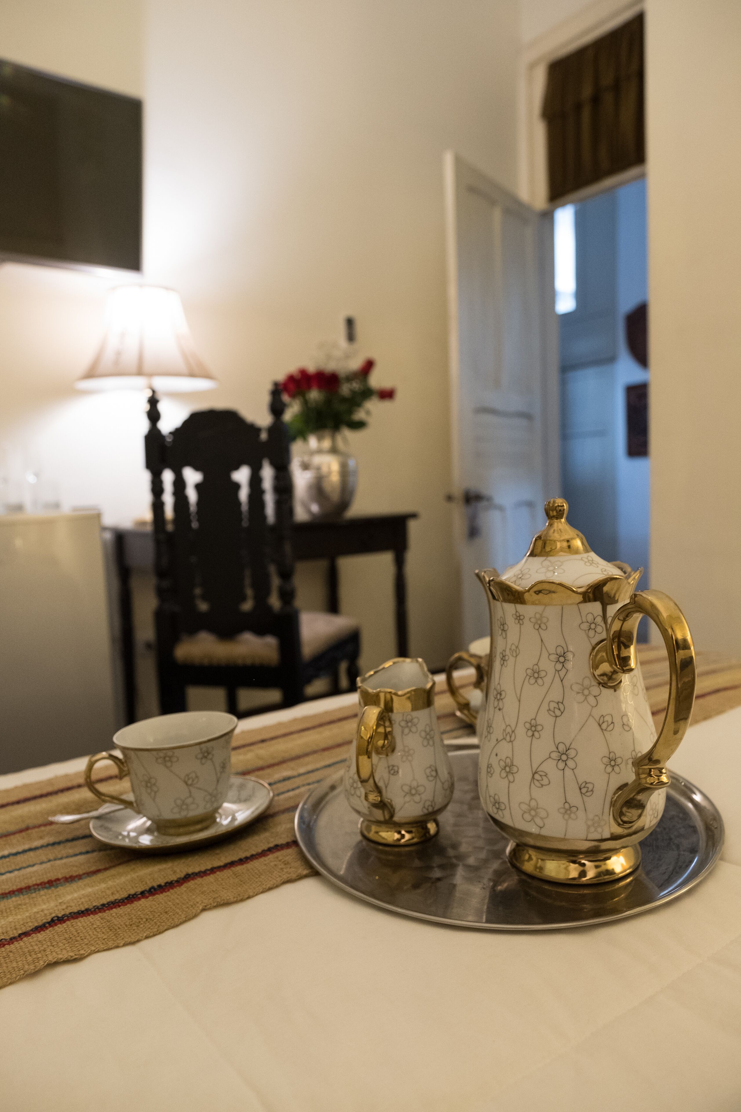 A tea set on a tray with a cup and saucer, a teapot, and a sugar bowl on a table.