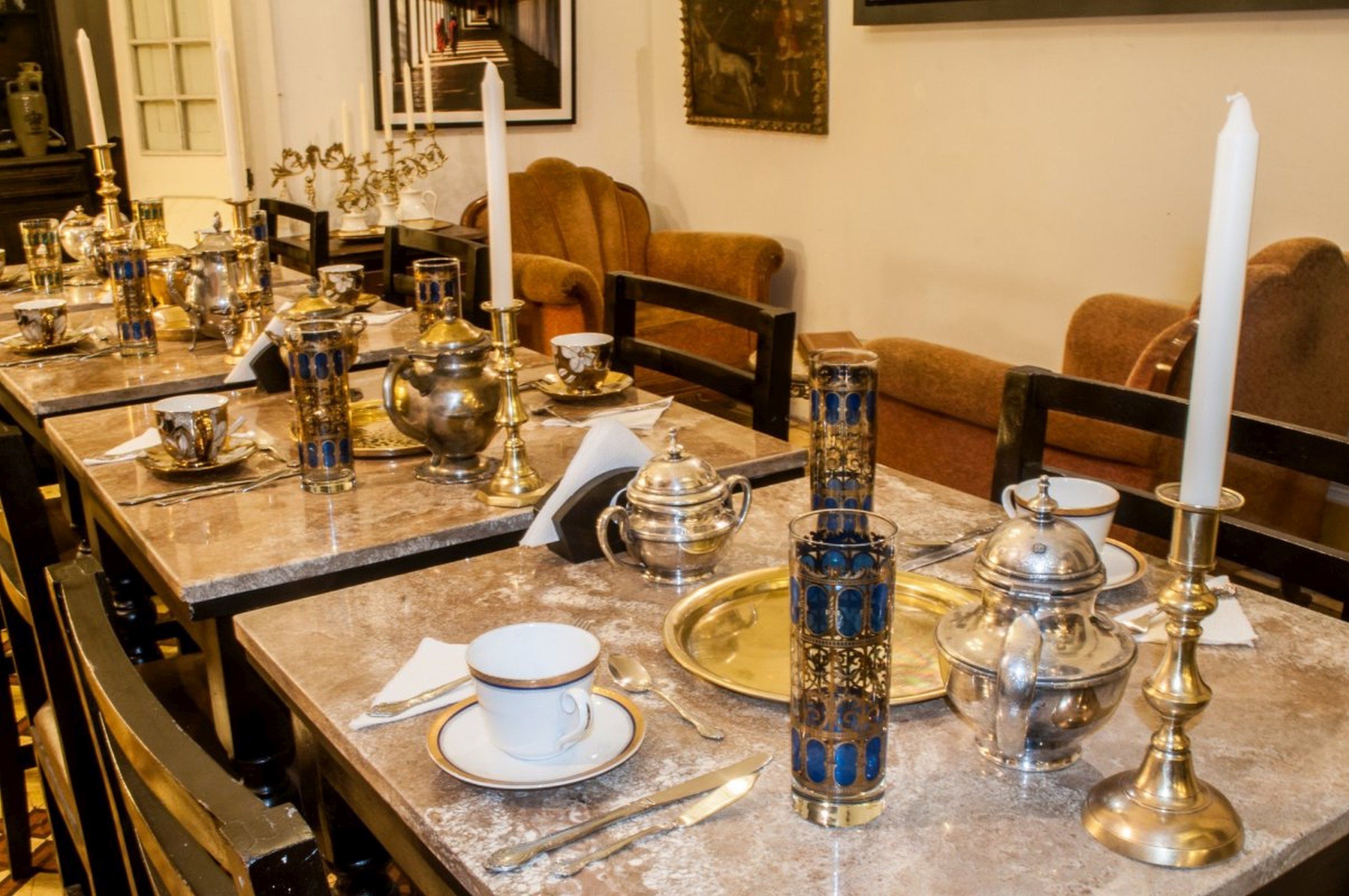 Een eetruimte met gedekte tafels voor een maaltijd, met bestek, borden en glazen.