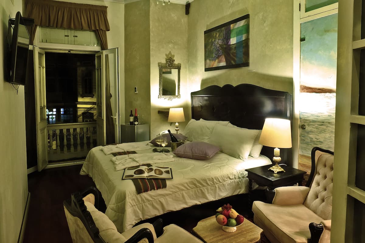 Ein Hotelzimmer mit Bett, Nachttischlampen, Obstschale, Stuhl und Meerblick.