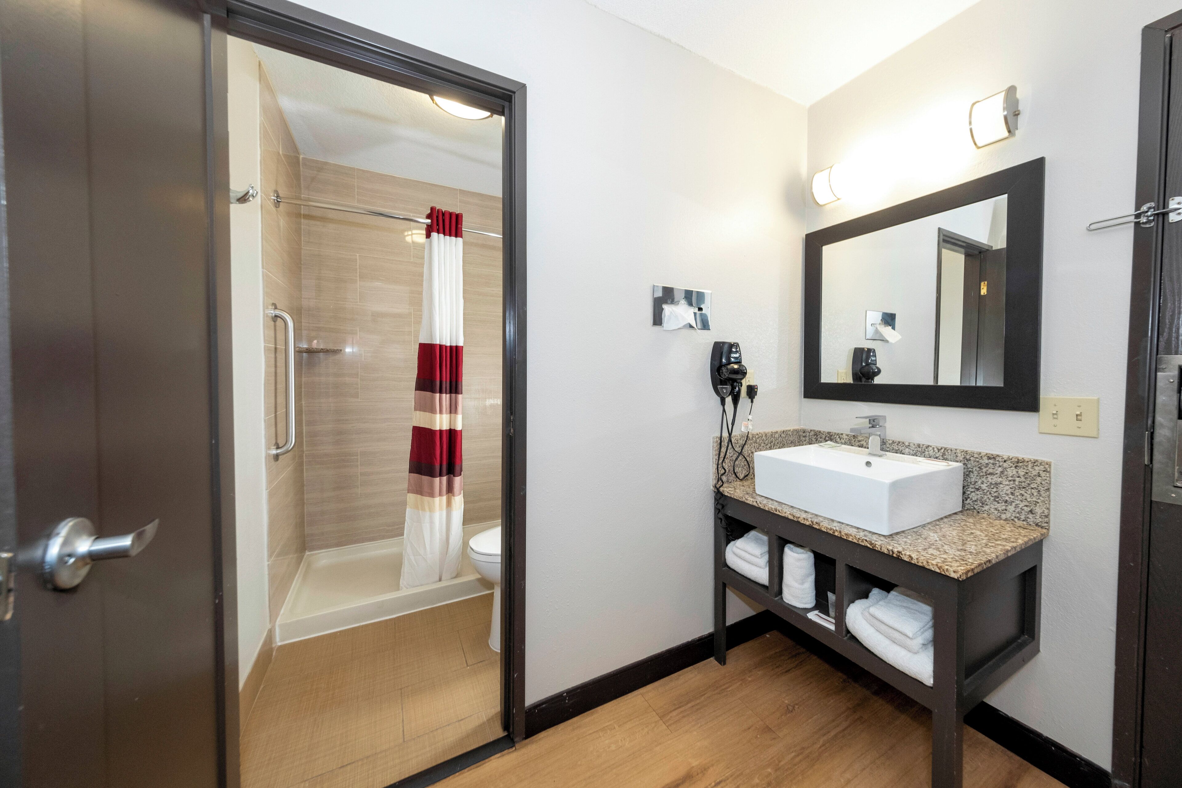 Een hotelbadkamer met douche, toilet, wastafel en een handdoekhouder.