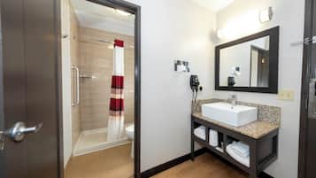 Een hotelbadkamer met douche, toilet, wastafel en een handdoekhouder.