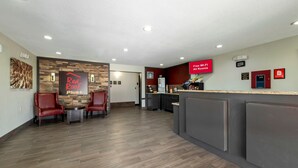 Vestíbulo de un hotel Red Roof Plus, con mostrador de recepción, zona de estar y un letrero de Red Roof Plus.