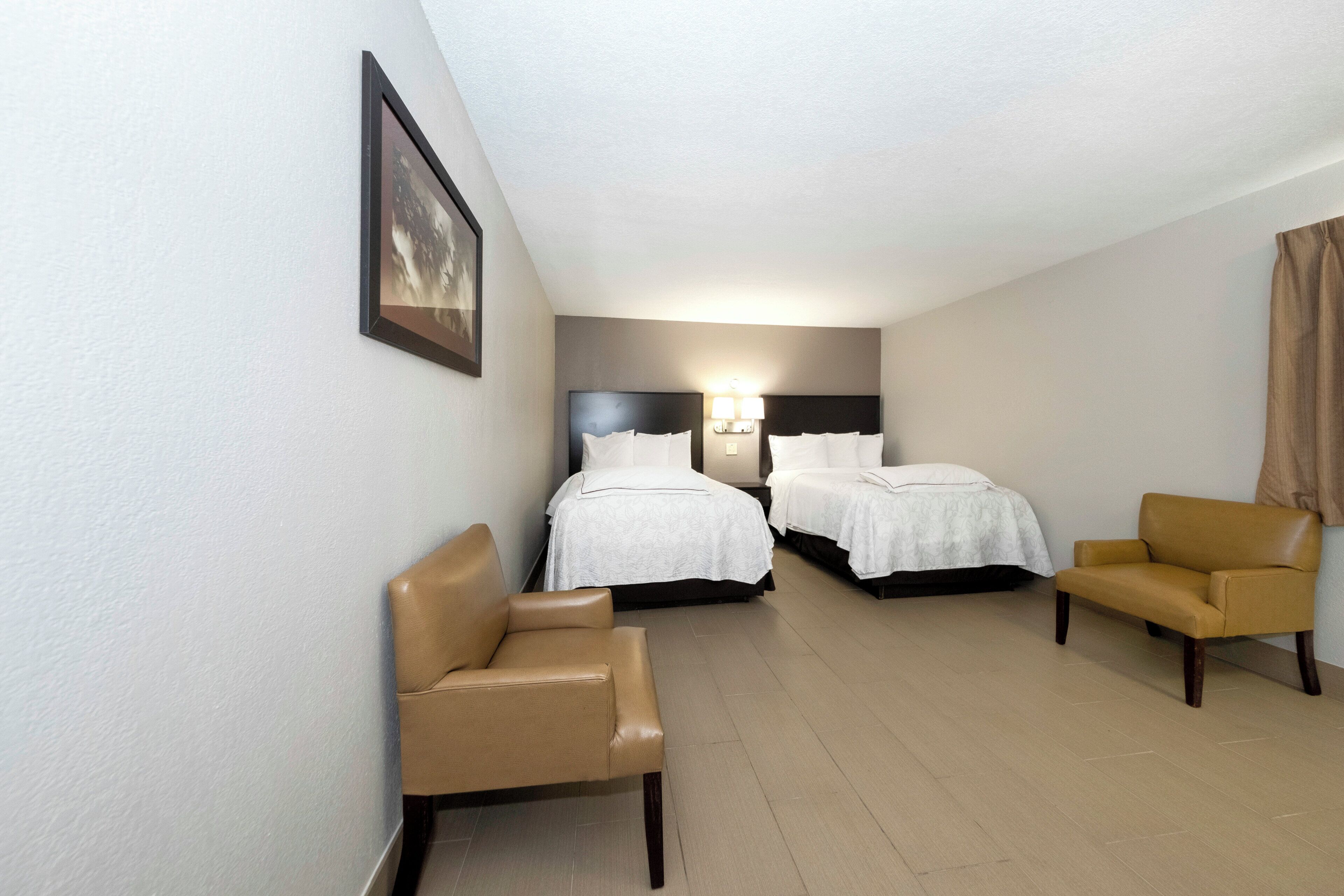 Ein Hotelzimmer mit zwei Betten, einer Sitzecke und einem gerahmten Bild an der Wand.