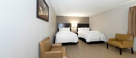 Ein Hotelzimmer mit zwei Betten, einer Sitzecke und einem gerahmten Bild an der Wand.