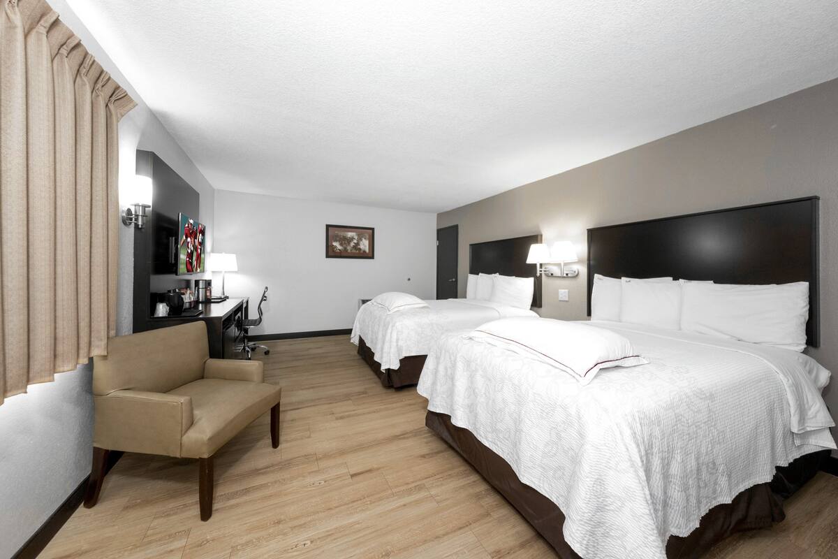 Ett hotellrum med två sängar, en soffa, ett skrivbord och en lampa.