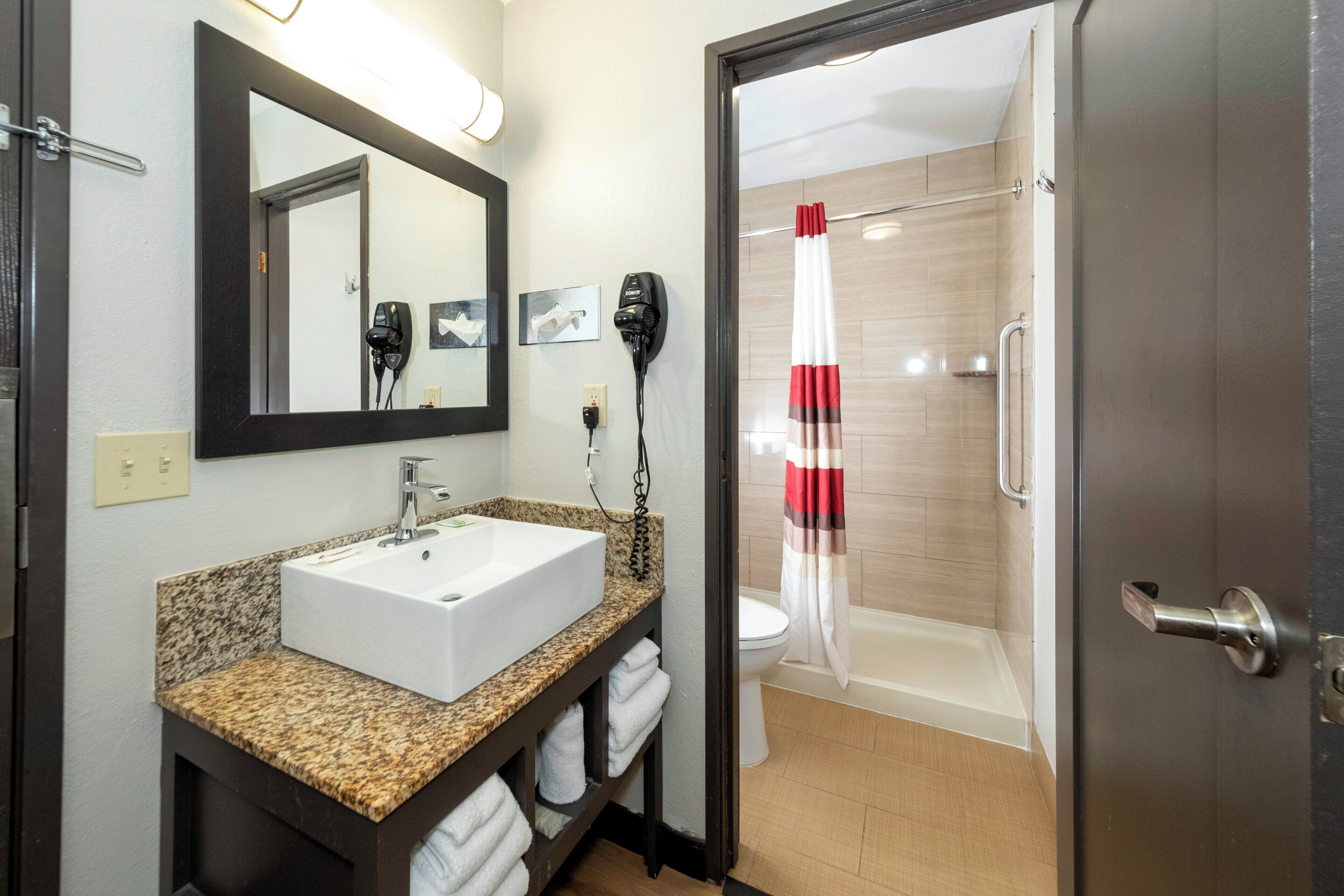A bathroom with a sink, mirror, hairdryer, and shower curtain.