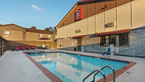 Un hotel con piscina, zona de estar al aire libre y un letrero Red Roof Plus.