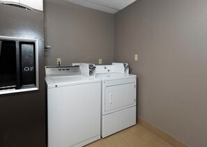 A laundry room with a washing machine and dryer, a utility wall, and a door with a push button.