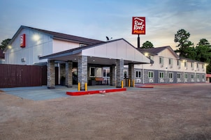 A Red Roof Plus hotel with a covered parking area and a building with a stone facade.
