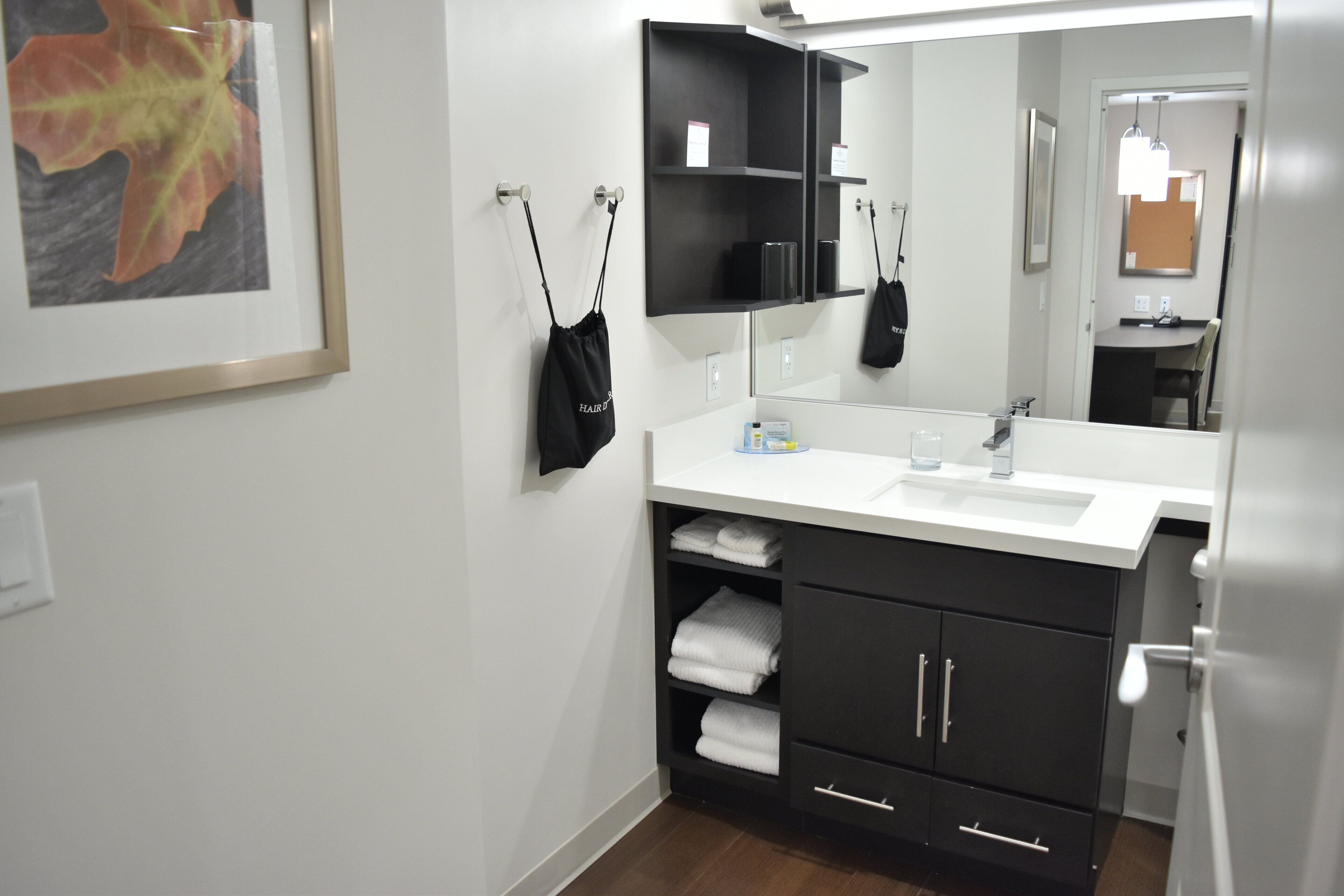 A modern bathroom with a white sink, black cabinets, and a mirror above the sink.