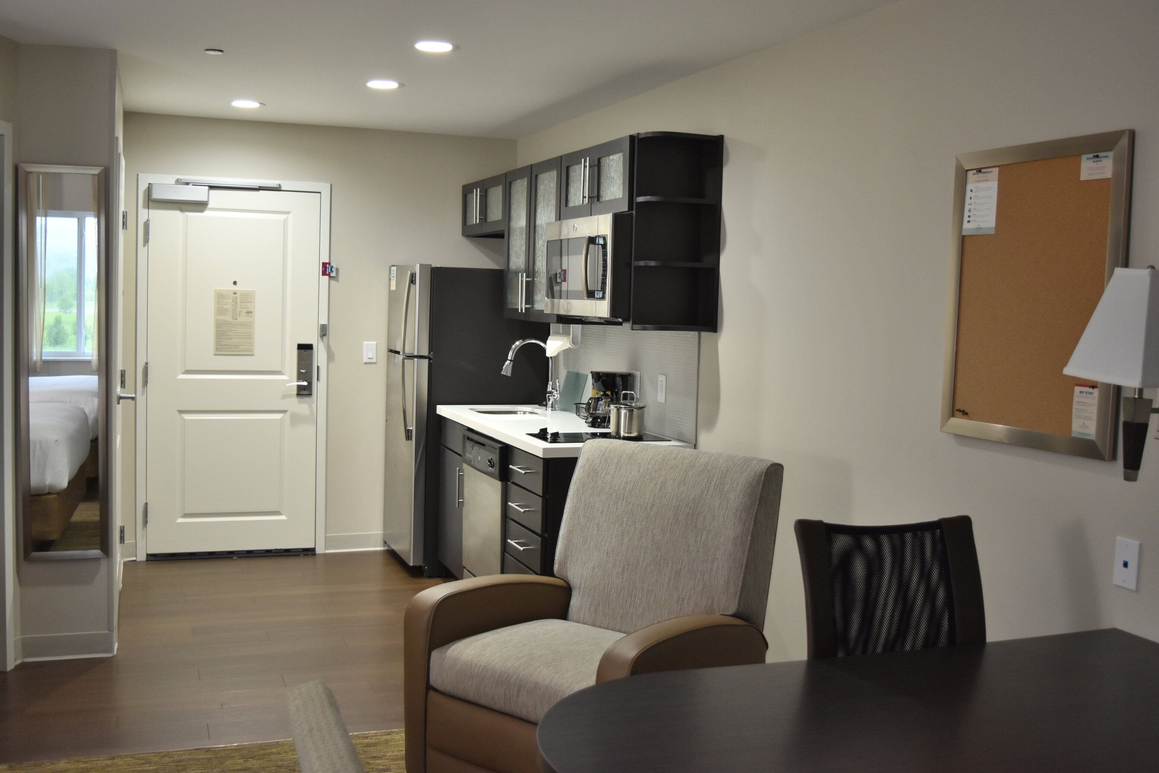 Una cocina compacta con electrodomésticos modernos, un comedor con mesa y sillas, y una puerta que da a un dormitorio.