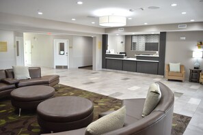 A hotel lobby with a reception desk, seating area, and a patterned carpet. - Candlewood Suites Kansas City - Independence by IHG (Independence)