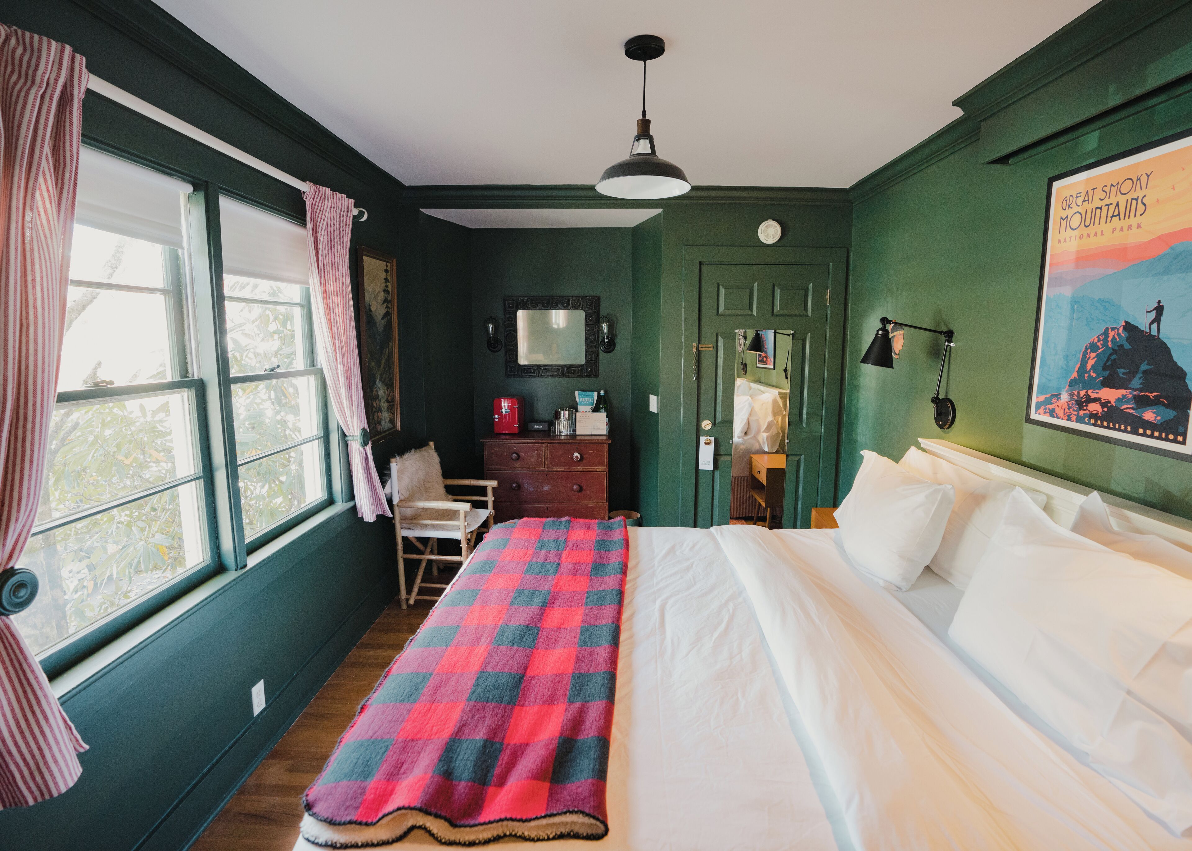 A room with a bed, a dresser, a chair, a desk, and a window with curtains.