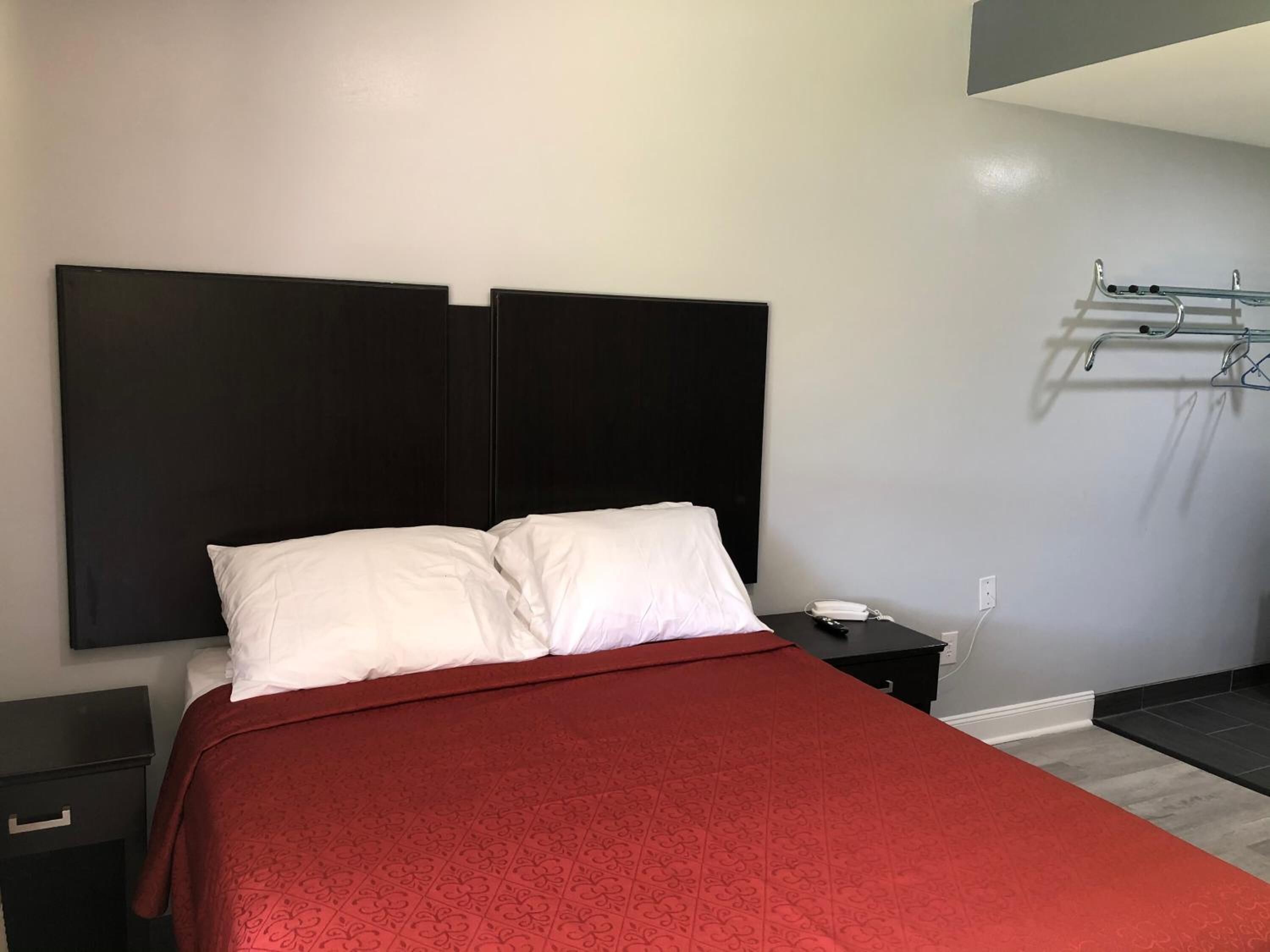A modern hotel room with a large bed, a bedside table, and a wall-mounted telephone.
