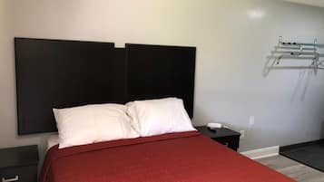 A modern hotel room with a large bed, a bedside table, and a wall-mounted telephone.