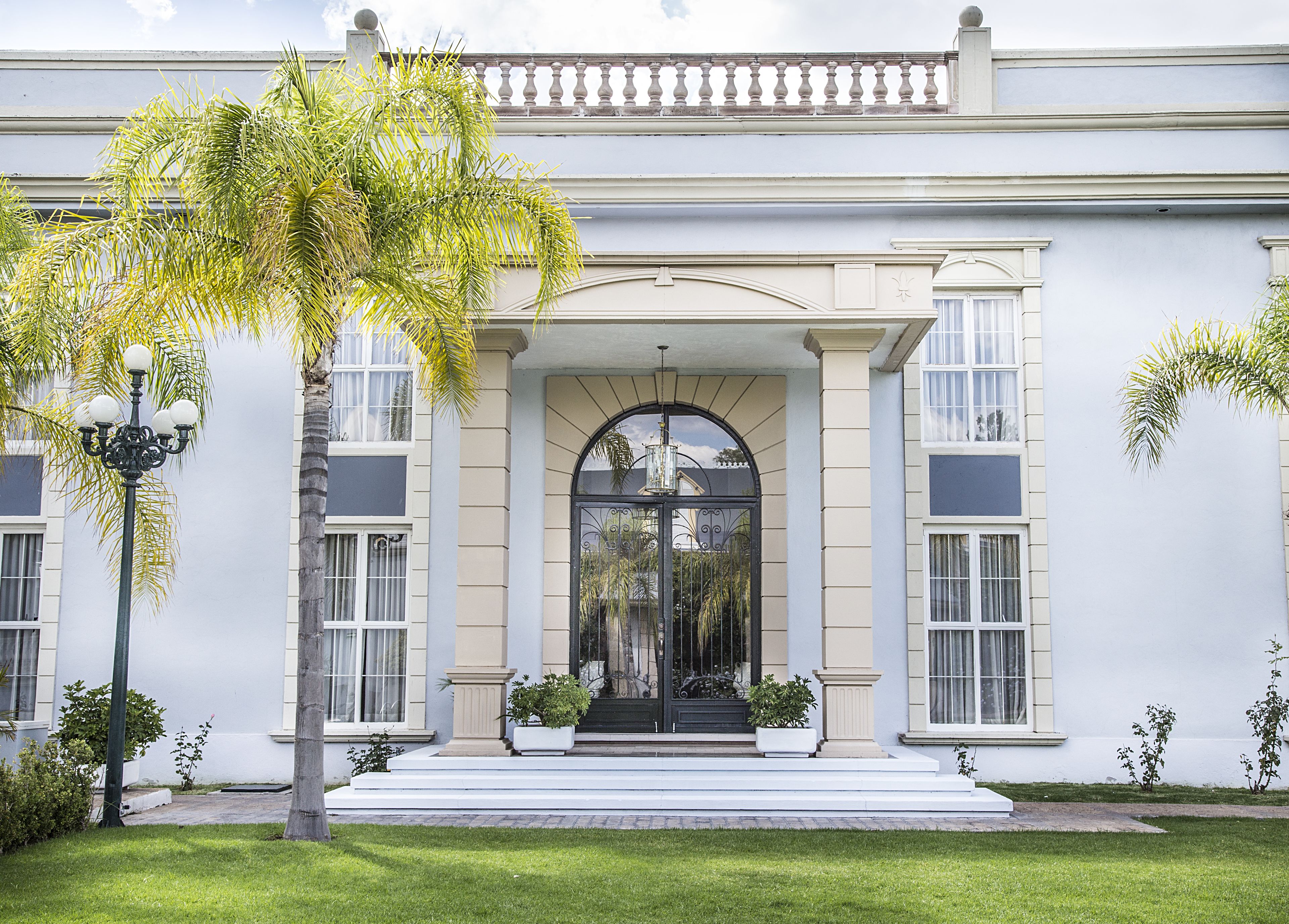 Um edifício imponente com uma entrada grandiosa, janelas amplas e um jardim bem cuidado.