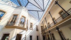 Un edifici de diverses plantes amb un sostre de vidre, múltiples balcons i un disseny arquitectònic clàssic.