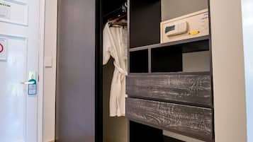 A modern closet with sliding doors, a robe hanging on a rack, and a small box on the top shelf.