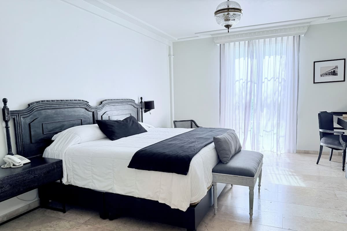 A modern bedroom with a large bed, bedside table, and a chair.