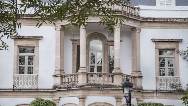 Facade d'un edifici clàssic amb finestres apuntades, un balcó central amb barana ornamentada i un disseny simètric.