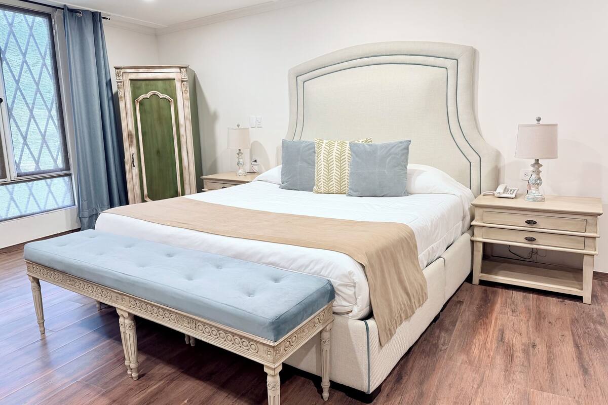 A bedroom with a bed, bedside tables, a bench, and a wardrobe.