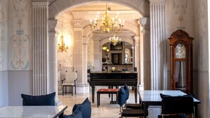 Un gran saló amb un piano, candelabres i arquitectura clàssica.
