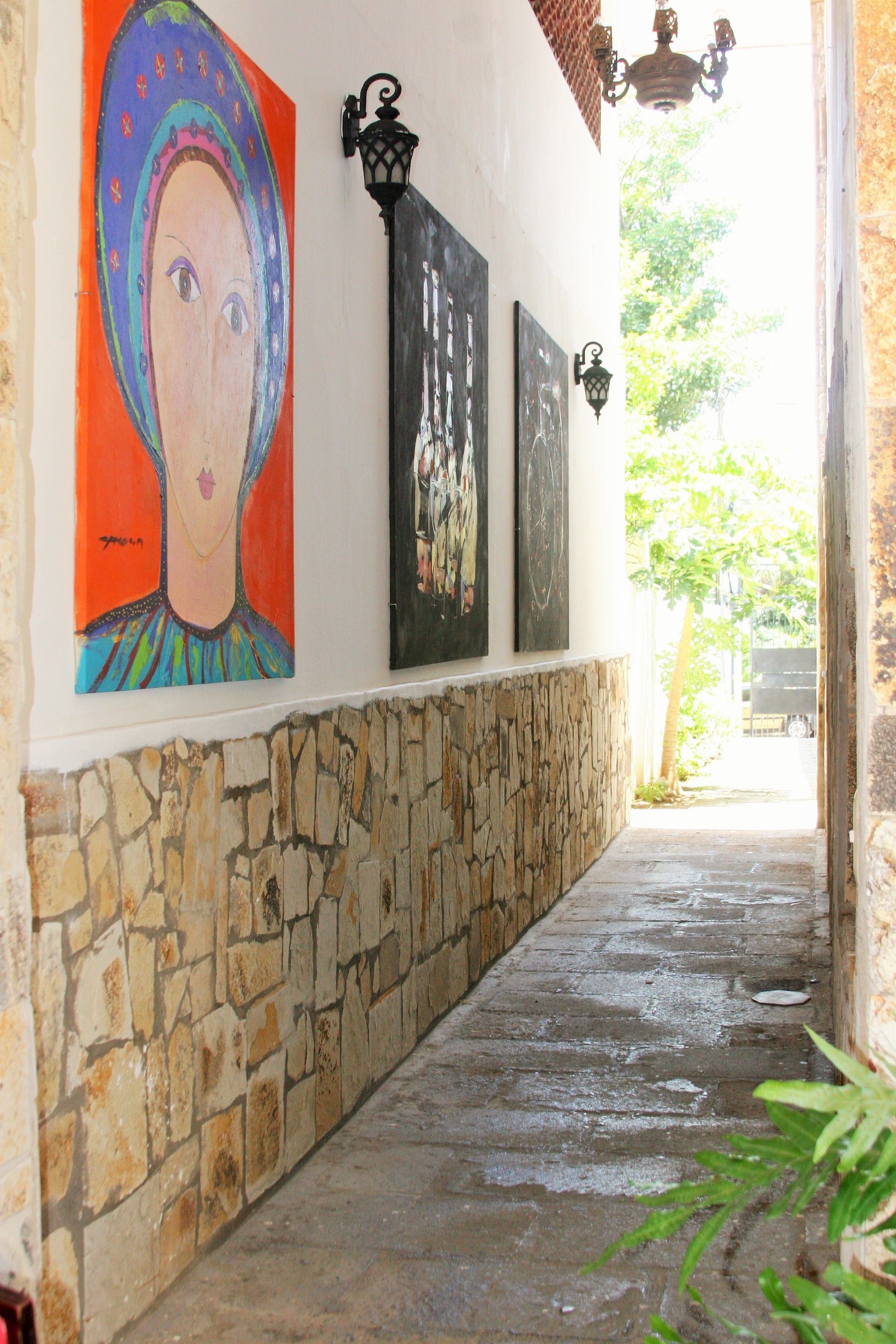 Un pasillo con paredes de piedra, suelo de baldosas y obras de arte en las paredes.