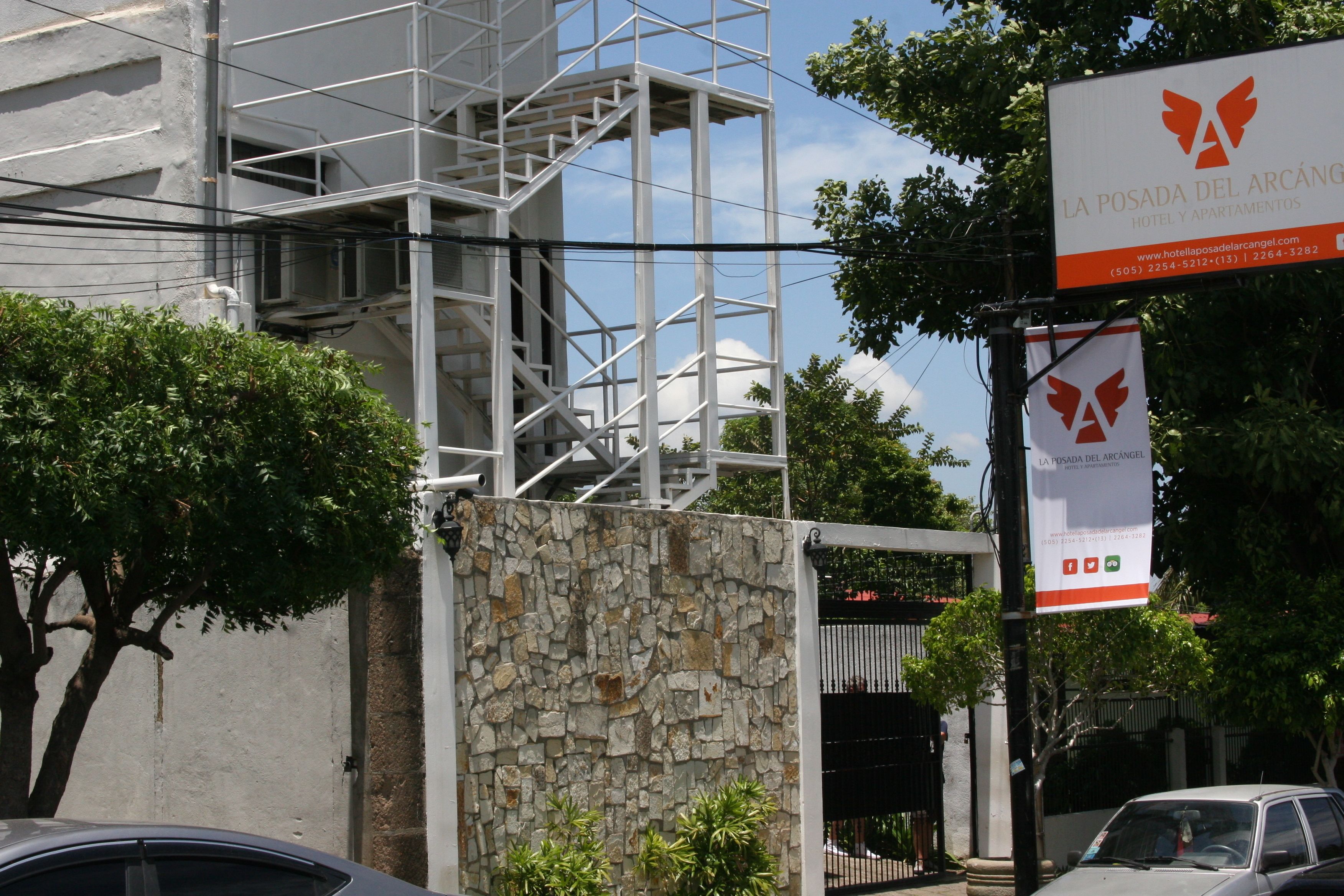 A hotel entrance with a stone wall and metal staircase.
