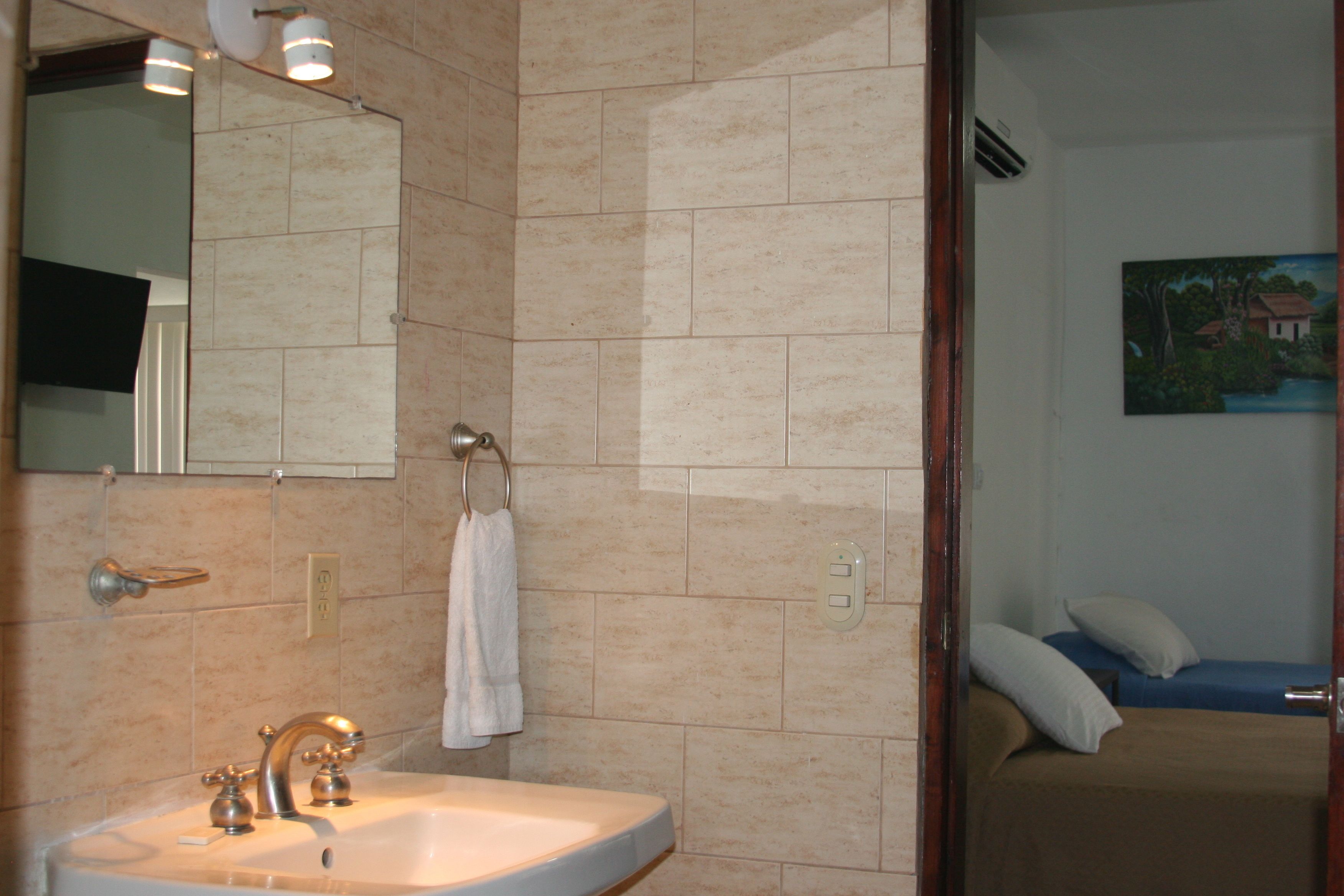 Un bagno con lavandino, specchio e asciugamano appeso al muro.