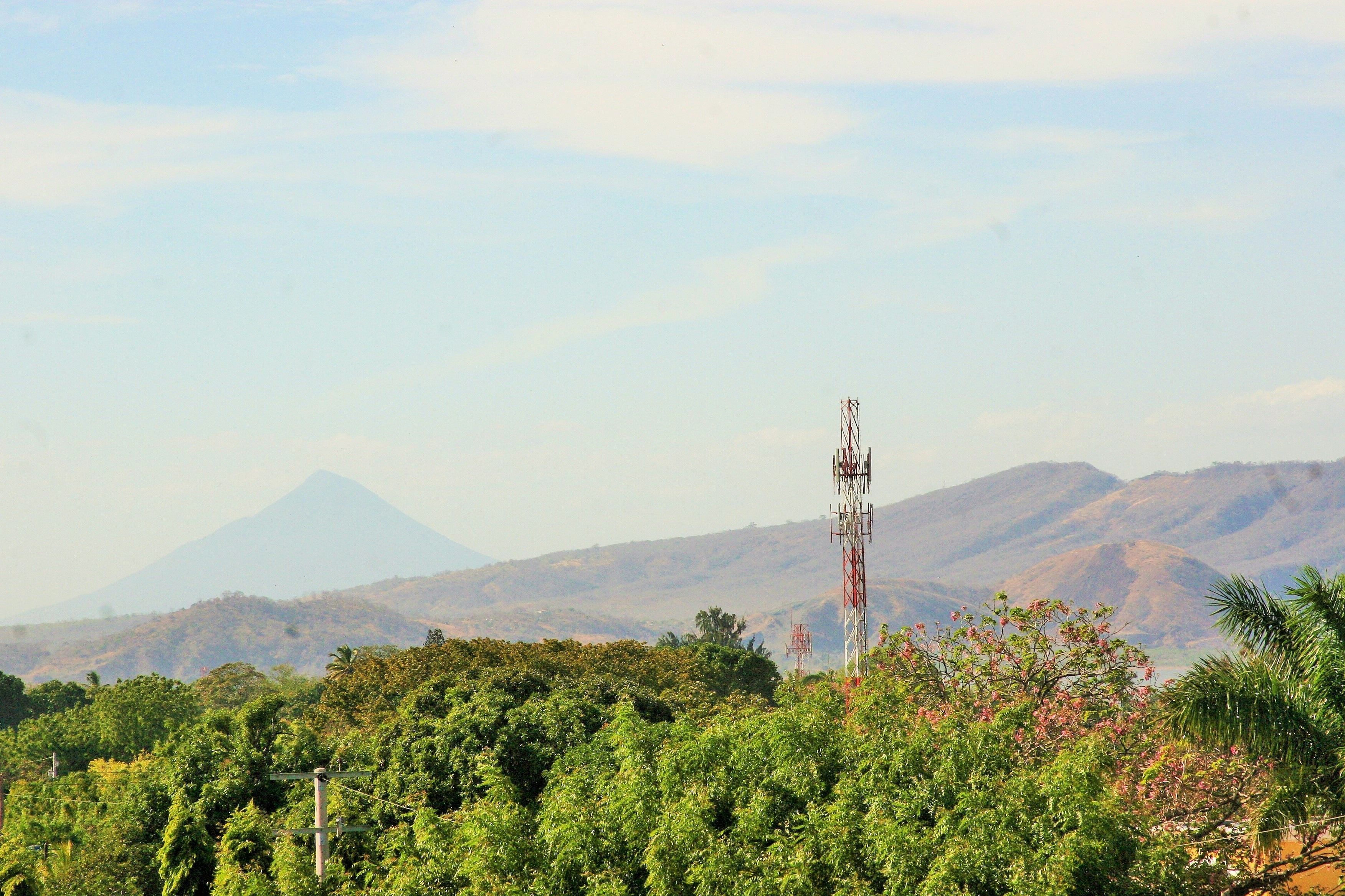 Eine gebirgige Landschaft mit einem Funkturm im Vordergrund und einem Berg im Hintergrund.
