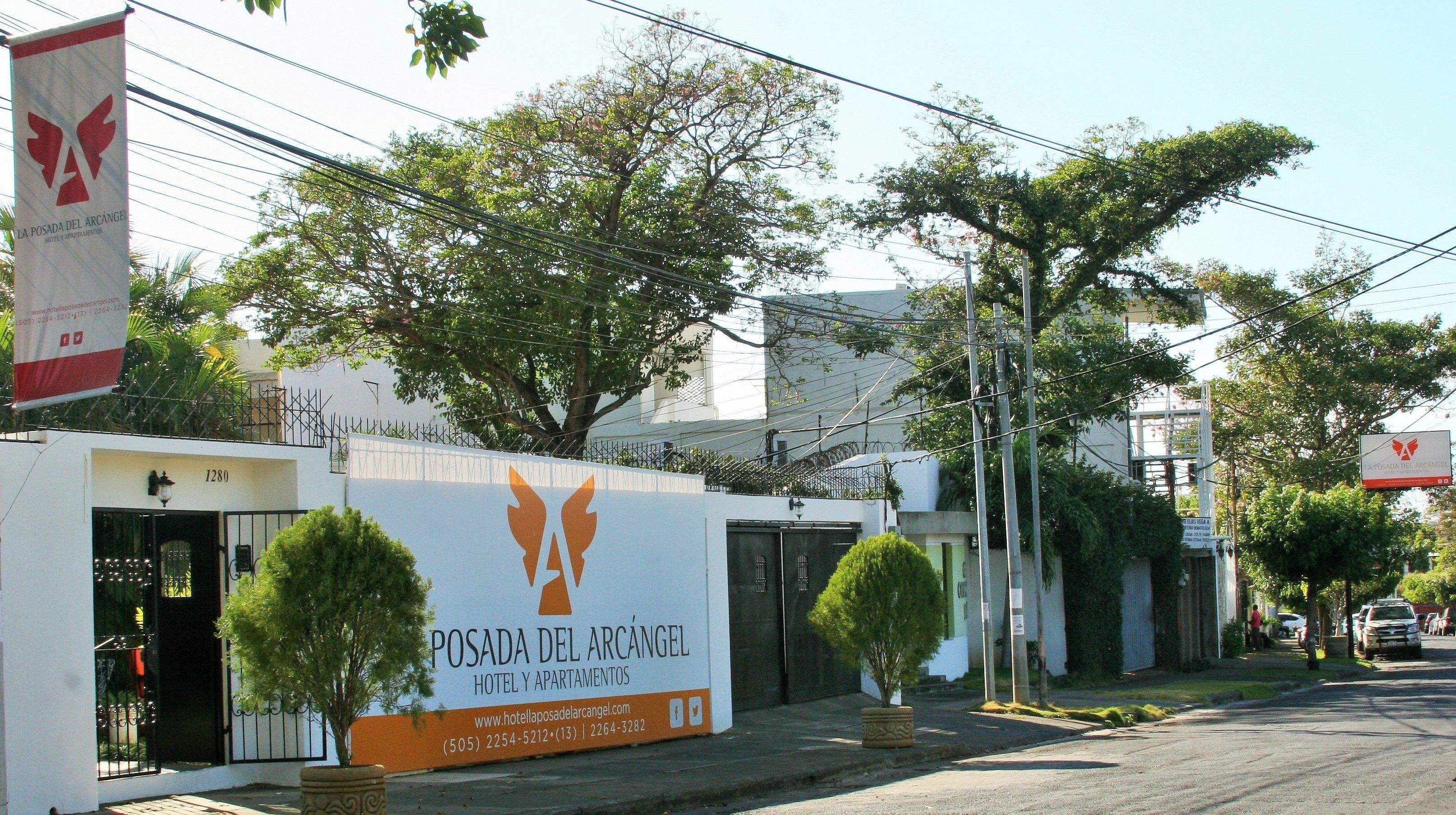 A hotel named Posada del Arcanel with a large sign, a gated entrance, and potted plants.