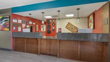 A reception area with a counter, wall-mounted certificates, and a computer.