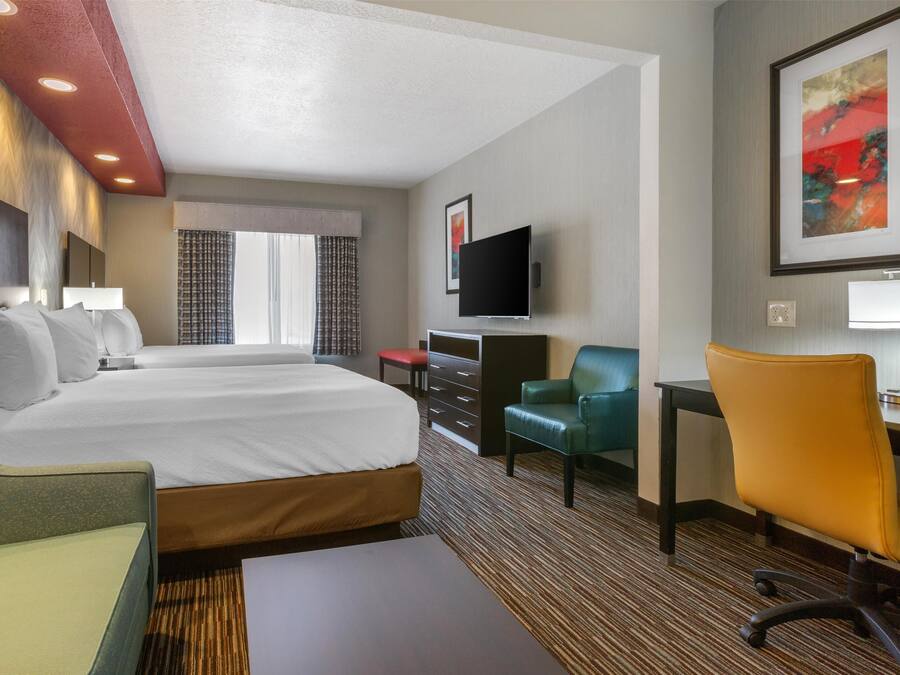 A hotel room with a large bed, a desk, a chair, a TV, and a painting on the wall.