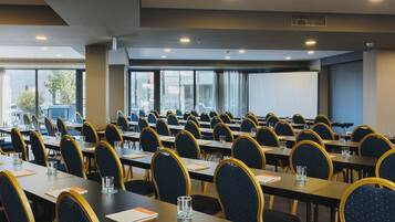 A conference room with rows of tables and chairs, large windows, and a view of the city.