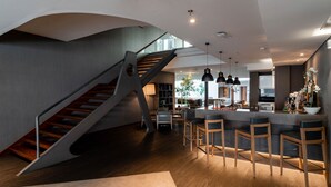 A modern interior with a staircase, bar area, and kitchen. - Timbre Heroismo (Porto)