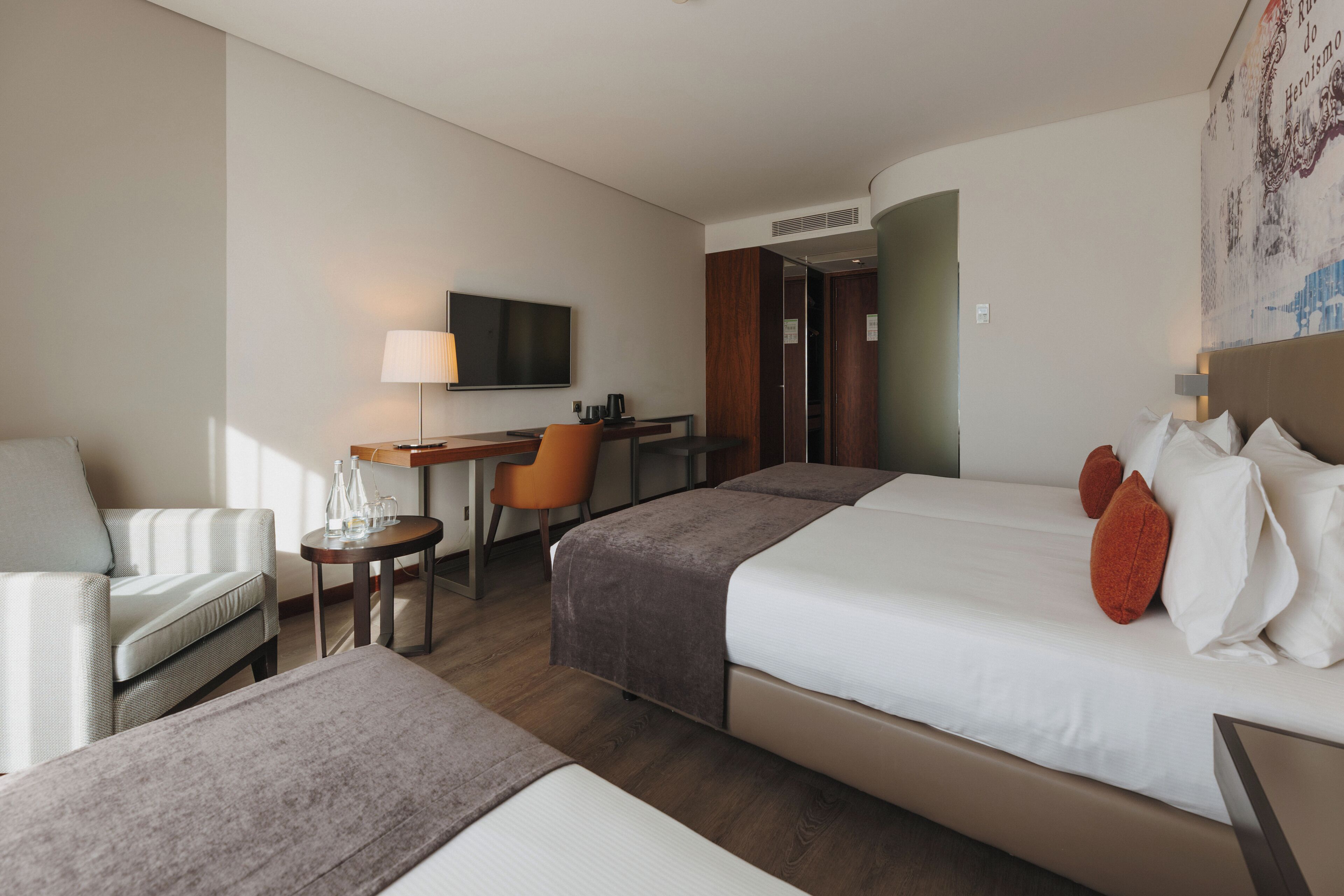 Una habitación de hotel con cama, escritorio, silla, sofá y televisor.