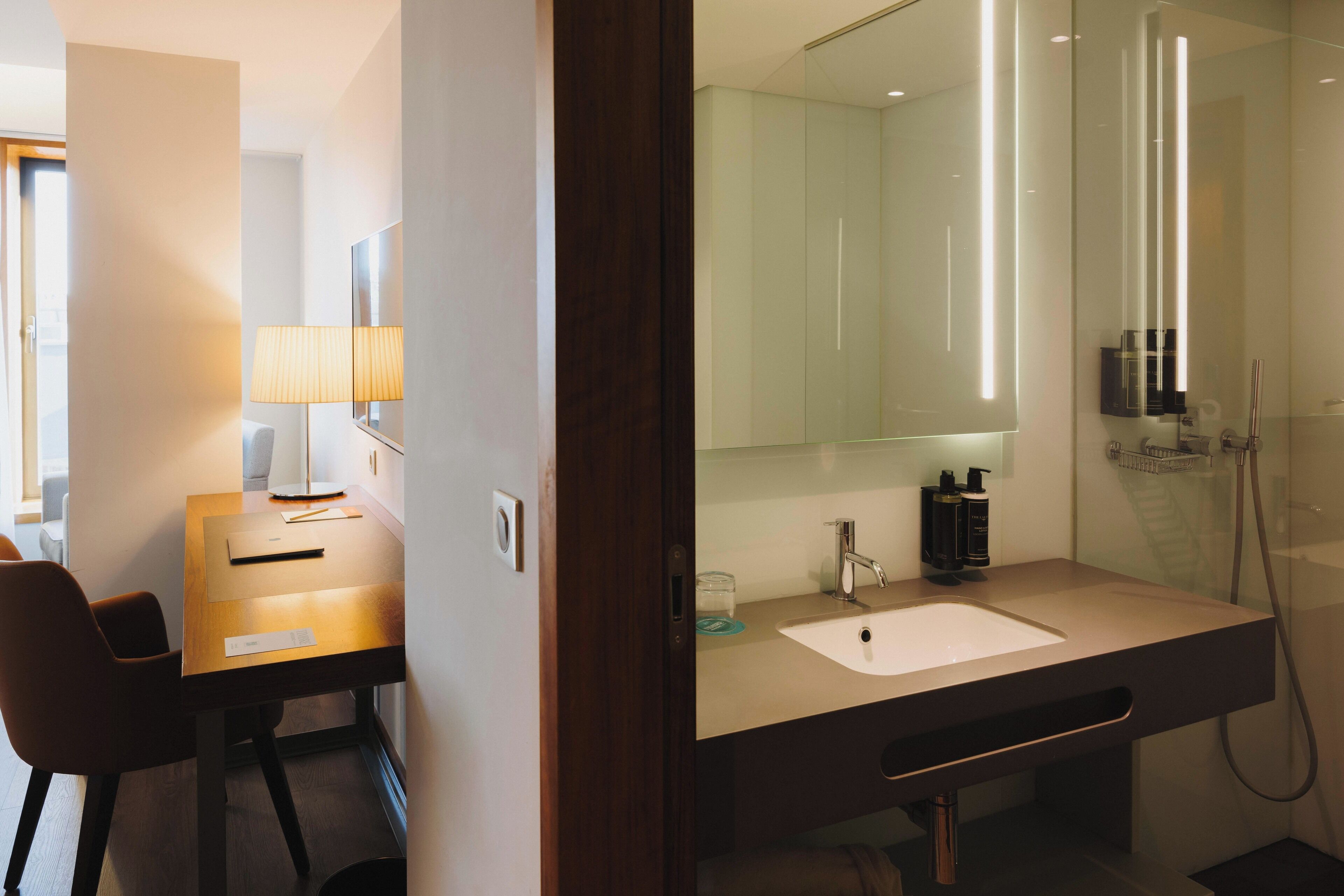 A modern bathroom with a large mirror, a sink, and a shower.
