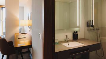 A modern bathroom with a large mirror, a sink, and a shower.
