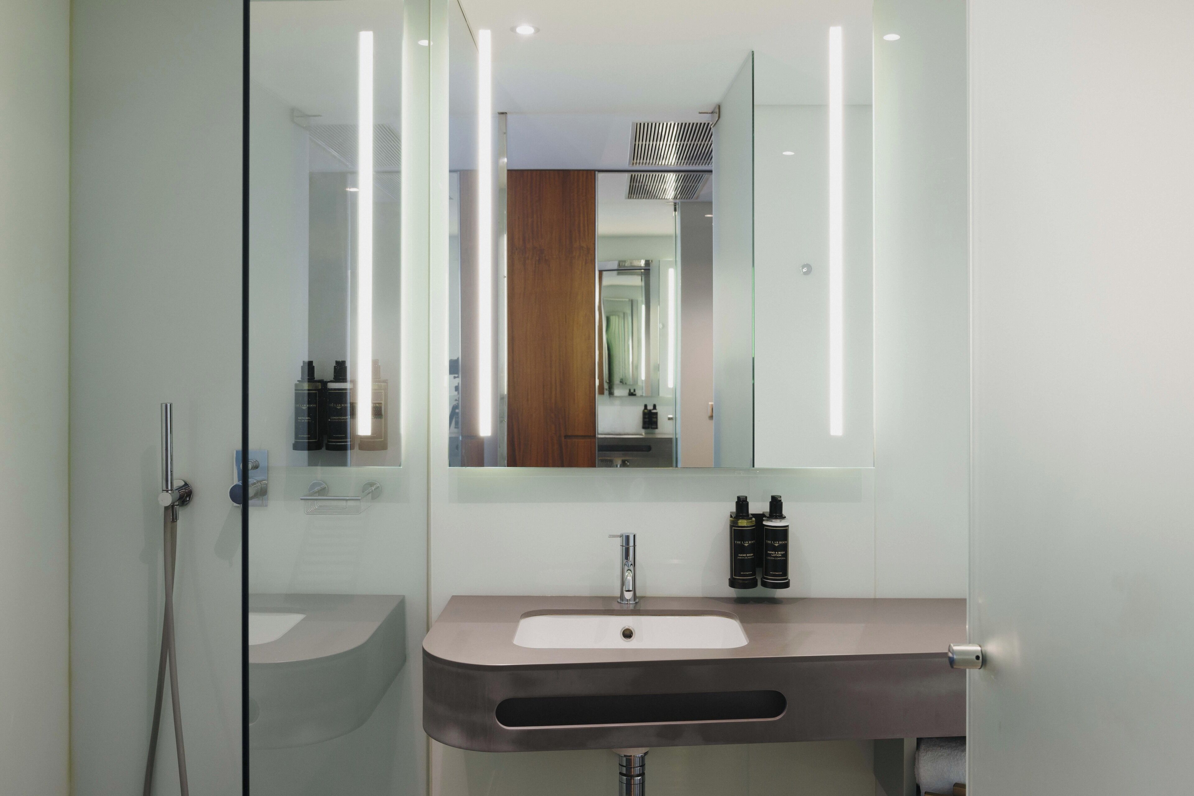Une salle de bain moderne avec une douche à parois de verre, un meuble-lavabo et un miroir.