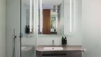 A modern bathroom with a glass shower enclosure, a vanity with a sink, and a mirror.